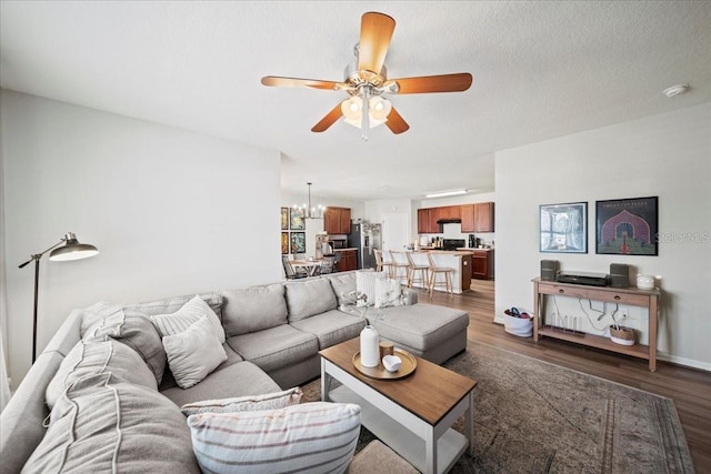 living area featuring a textured ceiling, wood finished floors, and ceiling fan with notable chandelier