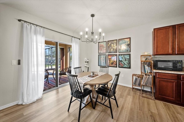 dining area featuring a notable chandelier, light wood-style flooring, baseboards, and a textured ceiling