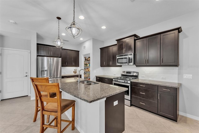 kitchen with decorative backsplash, dark stone counters, appliances with stainless steel finishes, dark brown cabinets, and a sink