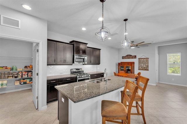 kitchen with a breakfast bar, stainless steel appliances, visible vents, decorative backsplash, and a sink