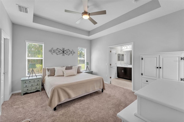 bedroom featuring a raised ceiling, visible vents, light carpet, and baseboards