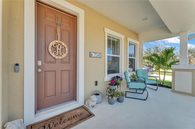 doorway to property featuring a porch and stucco siding