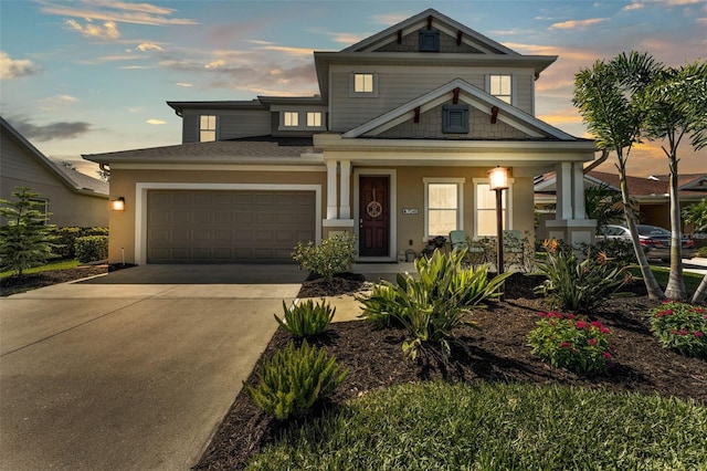 view of front of property featuring a garage, covered porch, driveway, and stucco siding