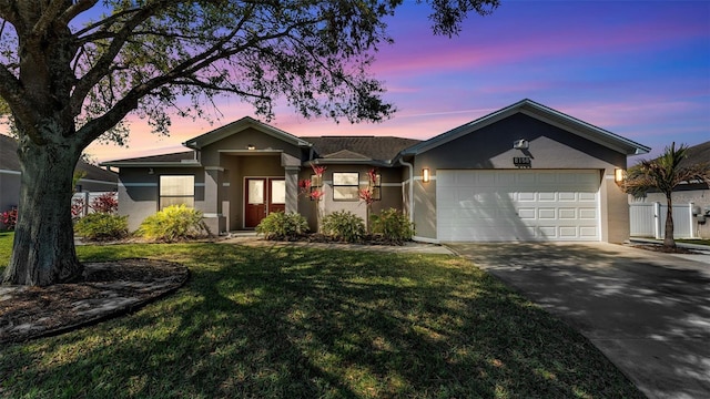 ranch-style home with driveway, a yard, an attached garage, and stucco siding