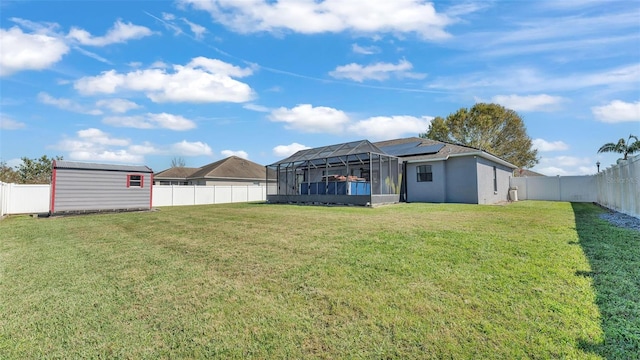 view of yard featuring a lanai, a storage shed, a fenced backyard, and an outdoor structure