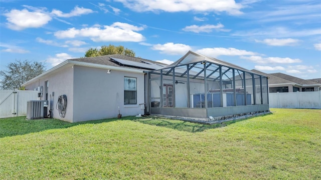 rear view of house featuring central AC unit, a fenced backyard, solar panels, a yard, and stucco siding