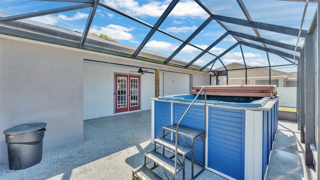 view of patio / terrace featuring french doors, glass enclosure, ceiling fan, and a hot tub