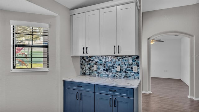 kitchen with a wealth of natural light, arched walkways, white cabinets, and tasteful backsplash