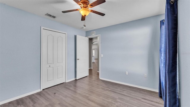 unfurnished bedroom featuring ceiling fan, wood finished floors, visible vents, and baseboards