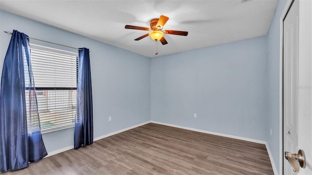 empty room featuring ceiling fan, wood finished floors, and baseboards