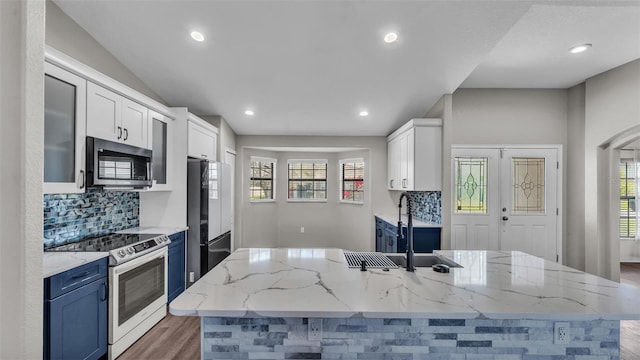 kitchen with stainless steel appliances, a sink, white cabinetry, decorative backsplash, and light stone countertops