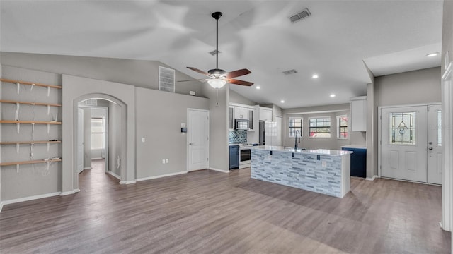 kitchen featuring appliances with stainless steel finishes, arched walkways, visible vents, and white cabinetry