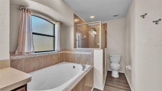 bathroom with a garden tub, toilet, wood finished floors, visible vents, and a stall shower