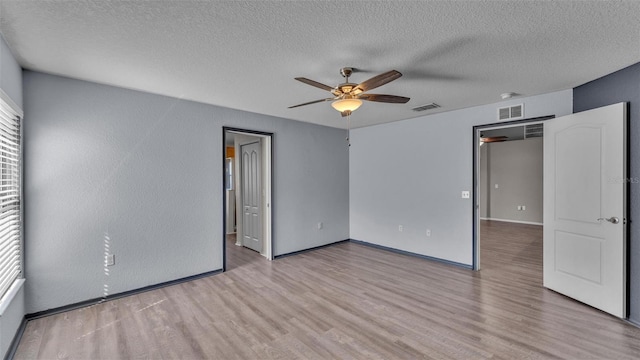 unfurnished bedroom with visible vents, a textured ceiling, baseboards, and wood finished floors