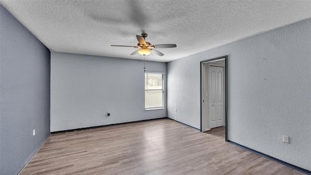 unfurnished room featuring a textured wall, wood finished floors, and a ceiling fan