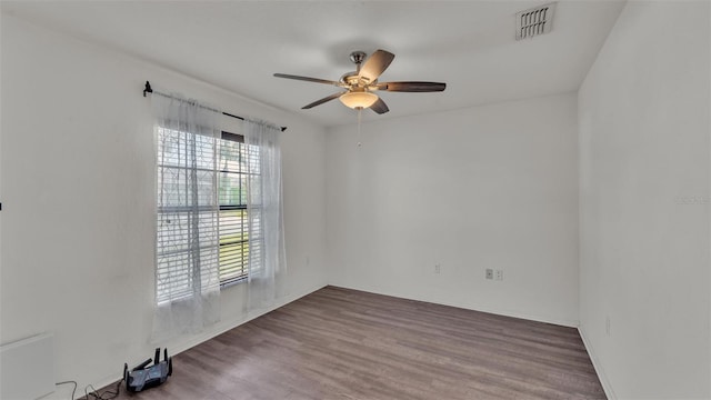 empty room featuring wood finished floors, visible vents, and a ceiling fan