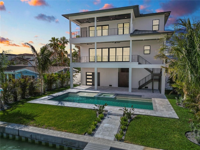 back of property at dusk featuring a patio, stucco siding, a balcony, and a ceiling fan