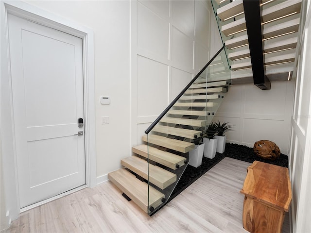 staircase featuring a decorative wall and wood finished floors