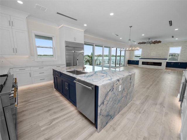 kitchen featuring high end appliances, visible vents, a sink, and white cabinetry