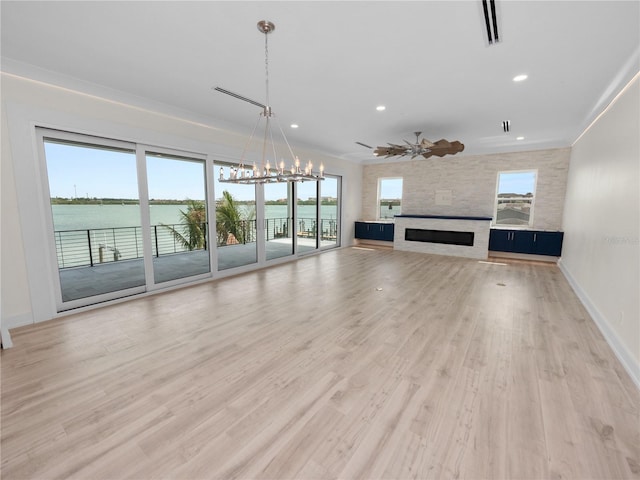 unfurnished living room featuring ceiling fan with notable chandelier, light wood-type flooring, a fireplace, and visible vents
