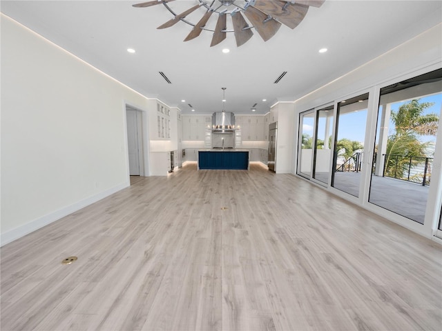 unfurnished living room with recessed lighting, light wood-style floors, a sink, ceiling fan, and baseboards