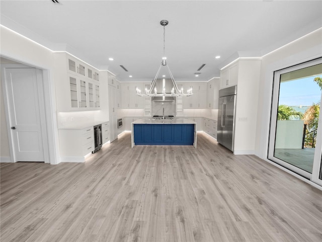 kitchen featuring built in fridge, wine cooler, a notable chandelier, light countertops, and white cabinets