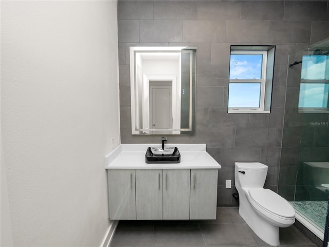 full bathroom featuring tiled shower, toilet, tile patterned flooring, vanity, and tile walls