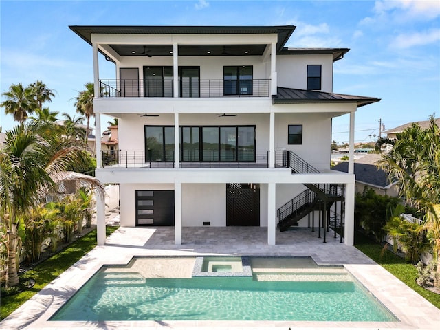 back of property featuring ceiling fan, a balcony, stucco siding, a standing seam roof, and a patio area