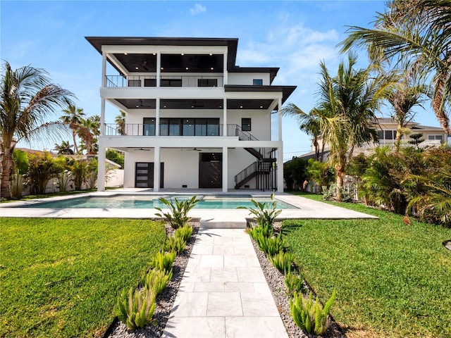 back of house featuring a balcony, stairs, a lawn, and a ceiling fan