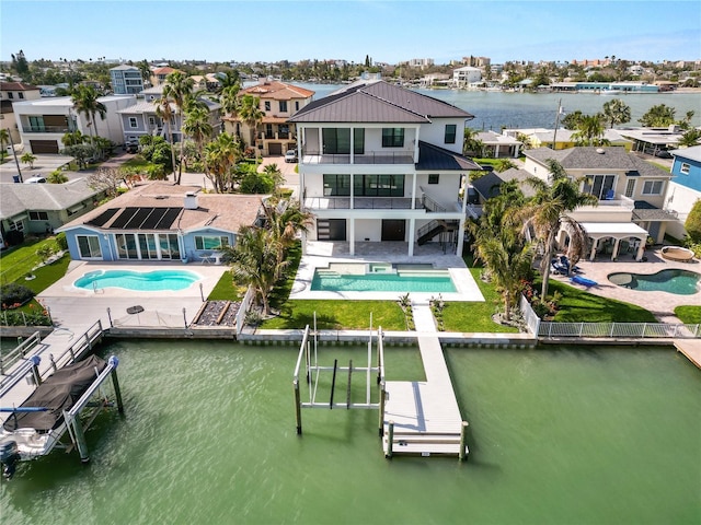 back of house featuring a patio, a balcony, a residential view, metal roof, and a water view