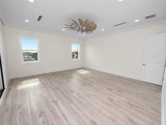 spare room with light wood-style floors, visible vents, and crown molding