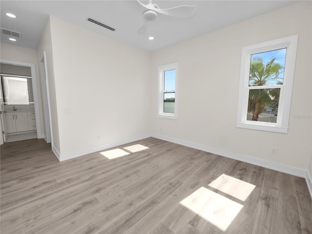 spare room featuring light wood-type flooring, visible vents, and a healthy amount of sunlight