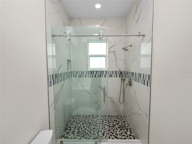 full bathroom with a marble finish shower and toilet