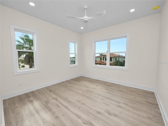 empty room with a ceiling fan, light wood-type flooring, plenty of natural light, and baseboards