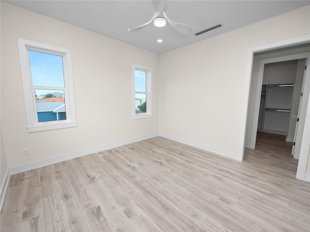 unfurnished bedroom with light wood-style flooring, visible vents, baseboards, a spacious closet, and a closet