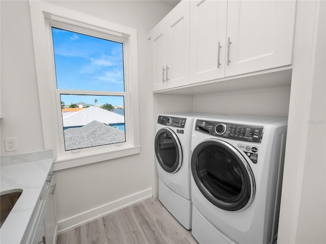 laundry area with light wood-style flooring, cabinet space, washer and clothes dryer, and baseboards