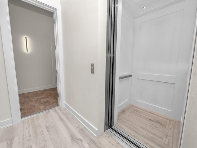 interior space featuring baseboards, elevator, and light wood-style floors