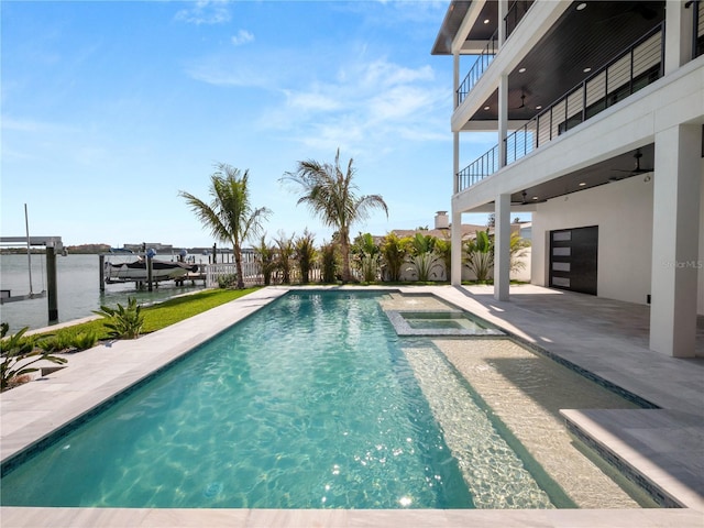view of swimming pool with a patio, boat lift, a water view, a pool with connected hot tub, and a dock