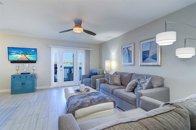 living room featuring a ceiling fan, baseboards, and light wood finished floors