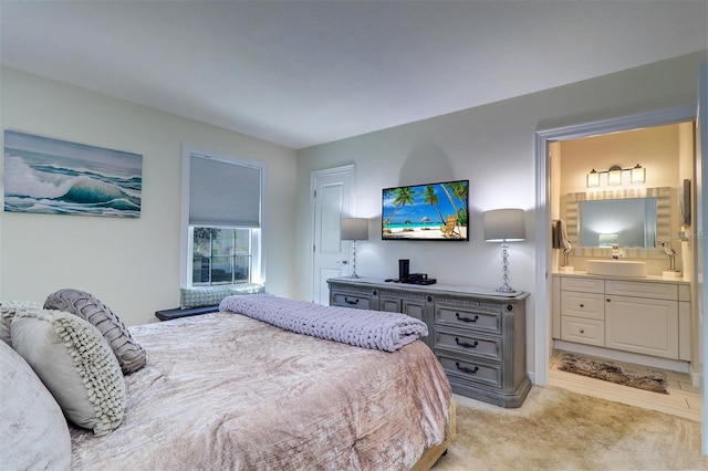 bedroom with light carpet, ensuite bathroom, and a sink