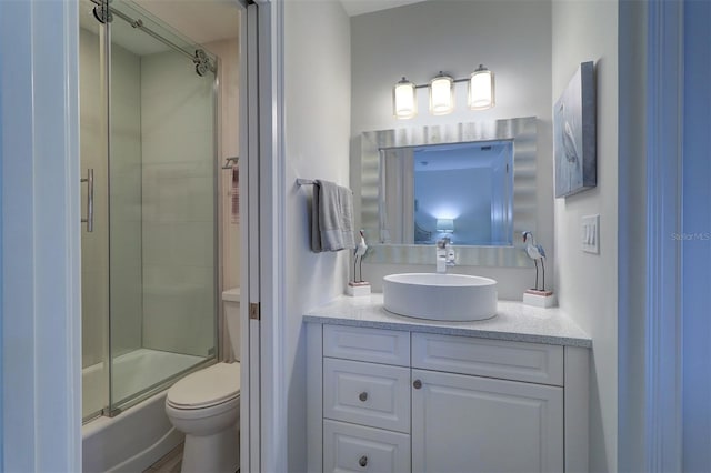 bathroom with combined bath / shower with glass door, toilet, and vanity