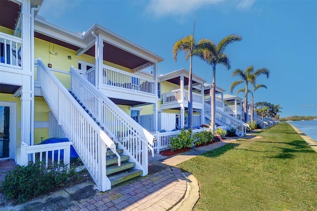 view of home's exterior featuring stairway, a lawn, and covered porch