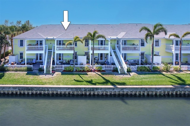 back of house featuring a water view, a lawn, a patio, and stairs