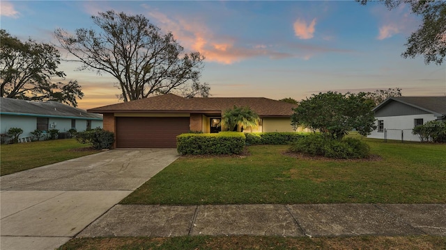 single story home with a garage, concrete driveway, a front lawn, and brick siding