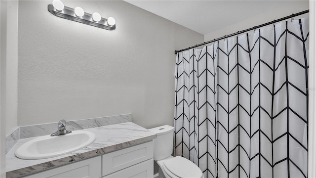 full bathroom with a textured wall, curtained shower, vanity, and toilet