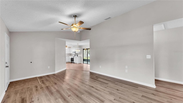 unfurnished living room featuring visible vents, light wood-style flooring, vaulted ceiling, a textured ceiling, and ceiling fan