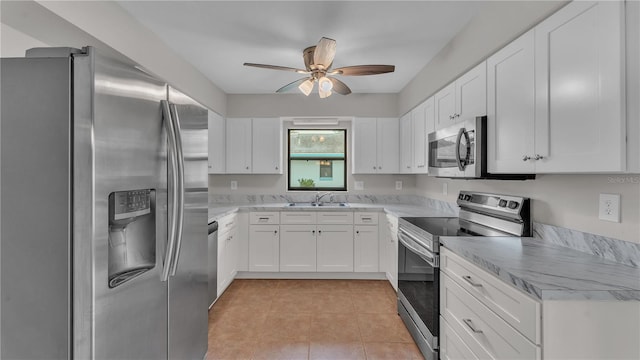 kitchen with stainless steel appliances, a ceiling fan, white cabinetry, and light tile patterned floors