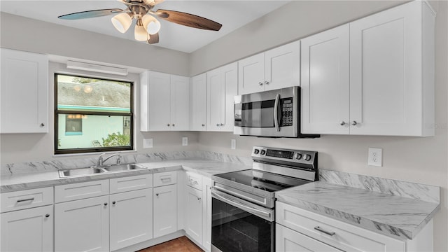 kitchen with stainless steel appliances, white cabinets, a sink, and a ceiling fan