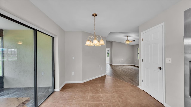 unfurnished room featuring ceiling fan with notable chandelier, baseboards, and light tile patterned flooring