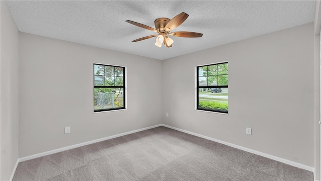 empty room with a textured ceiling, ceiling fan, carpet flooring, and baseboards